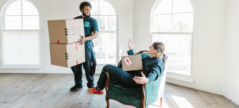 two guys carrying moving boxes and talking about tips for moving household goods