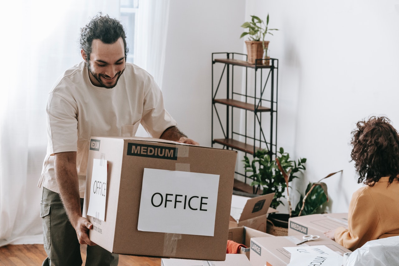 A man in white with a moving box labeled 'office'