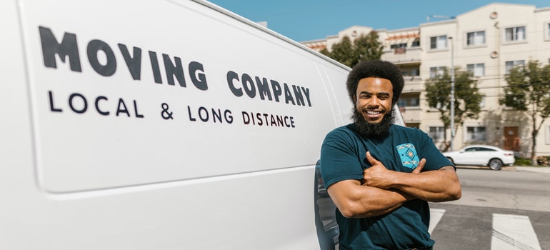 A mover professional leaned on a van;