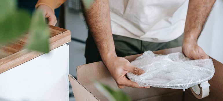 A man packing a plate into a moving box