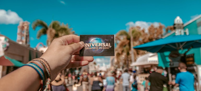 A person holding a universal studios ticket in his hand, while thinking about why are people moving to Orange County Florida;