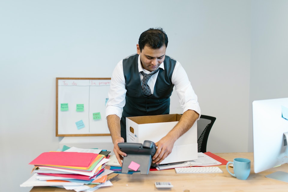 A man packing his things and thinking about how to safely store office equipment;