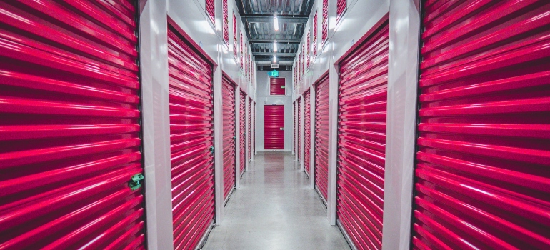 a picture of the interior of a storage unit facility with red storage unit doors all around