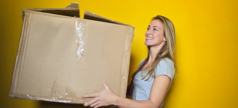 A woman holding a packed moving box
