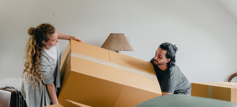 Two people carrying a cardboard box and getting ready for Seminole County movers