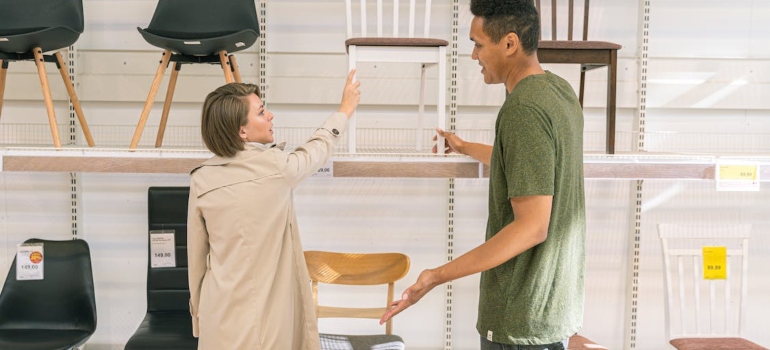 a man and a woman looking at chairs at the furniture shop