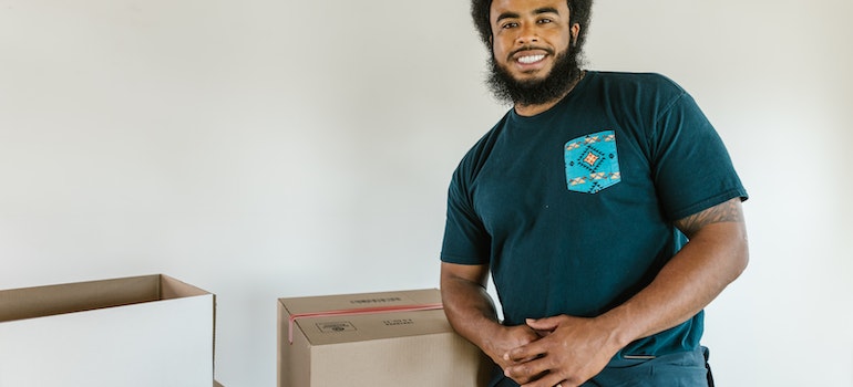 A smiling mover standing next to some moving boxes