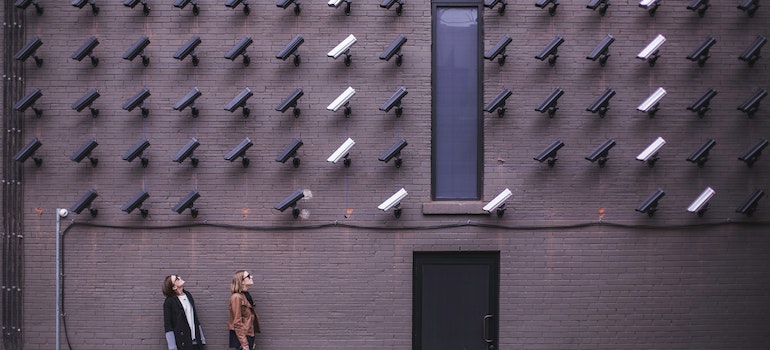 Man and woman looking at many cameras on wall;