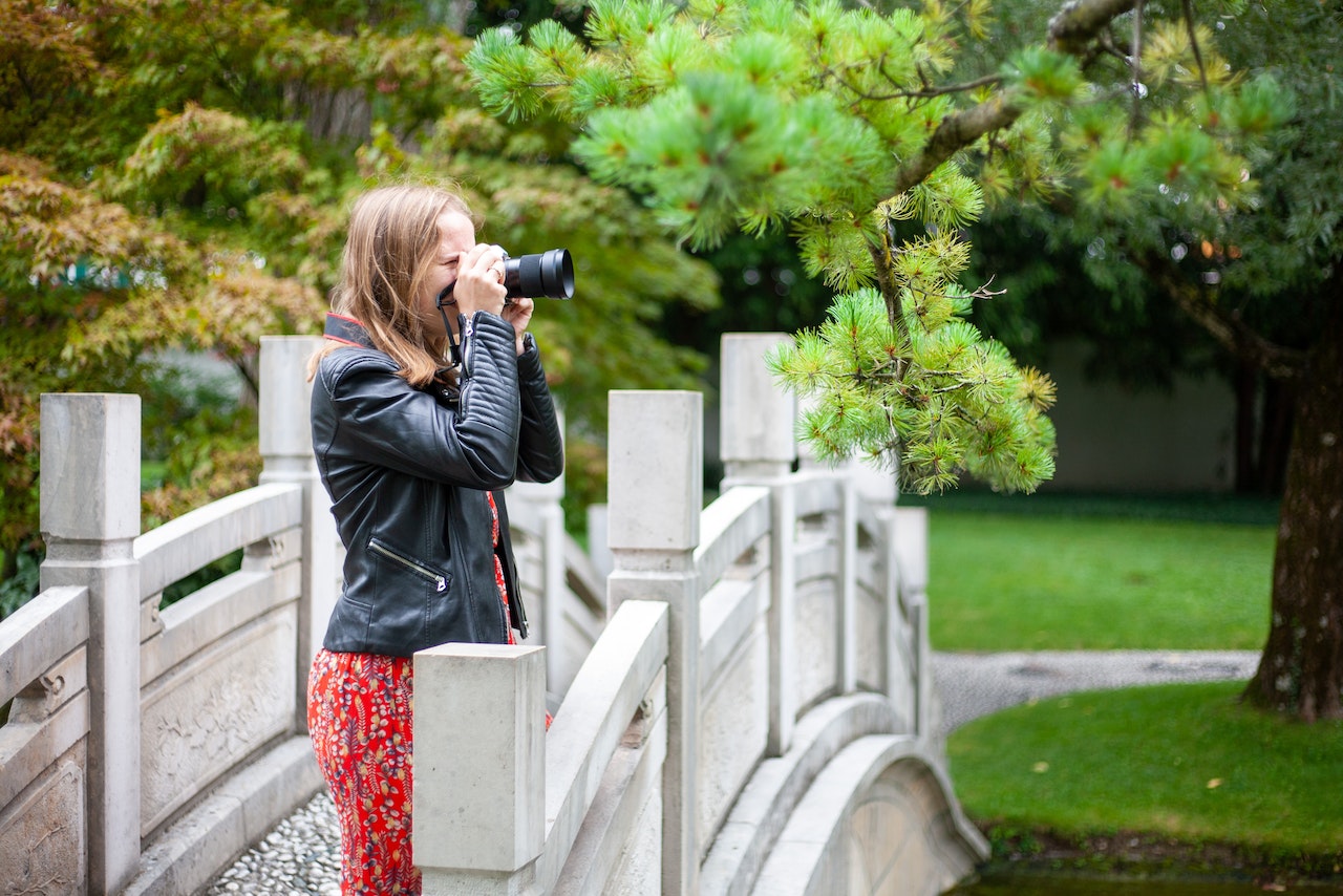 A woman holding a camera while standing on the bridge