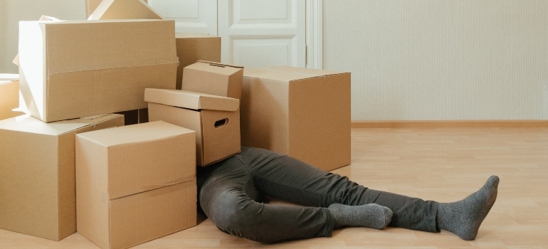 Man laying under moving boxes