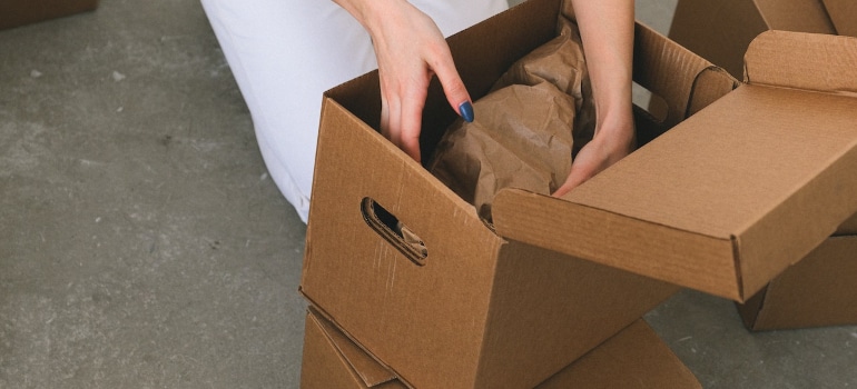 A woman puts items in a box as means of pecautions to take during relocation
