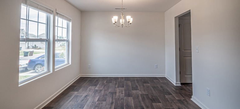 Empty room with a wooden floor and chandelier and large windows