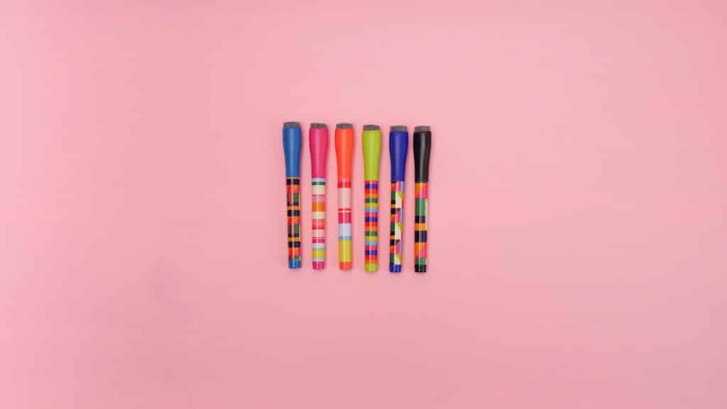 Picture of colorful markers on a pink surface