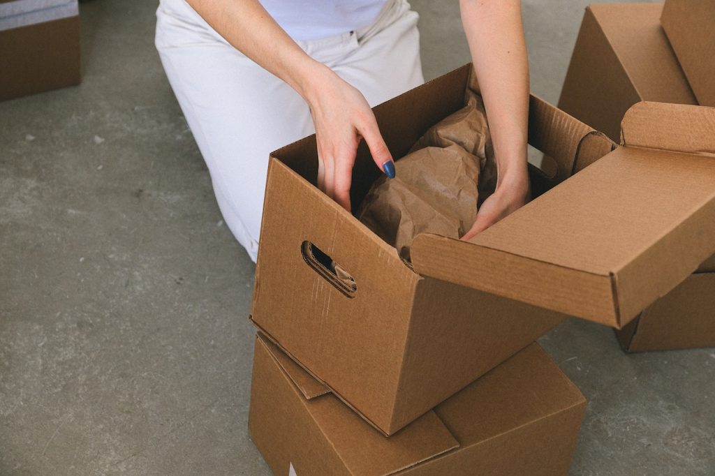 faceless woman packing belongings into cardboard box before relocation