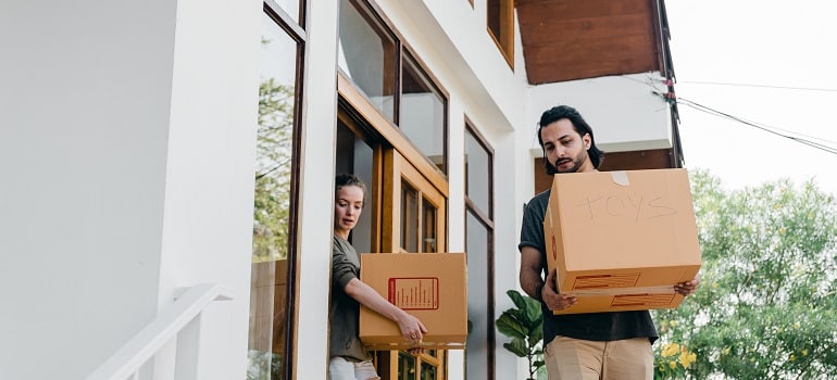 a couple carrying moving boxes