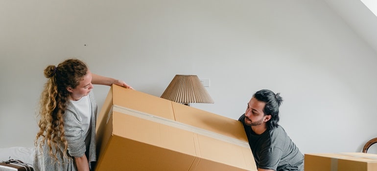 a couple carrying a moving box